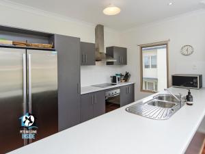 a kitchen with a sink and a refrigerator at Contemporary Golf Course Frontage 3BR in Normanville