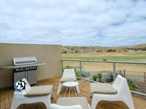a patio with white chairs and a grill on a deck at Contemporary Golf Course Frontage 3BR in Normanville