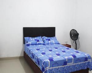 um quarto com uma cama com um edredão azul e uma ventoinha em Casa Albina em Yurimaguas