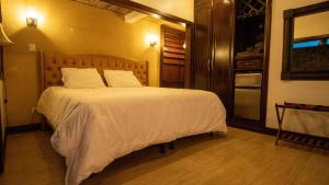 1 dormitorio con 1 cama grande con sábanas blancas en Hotel Poza Blanca Lodge, en San Mateo