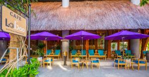 ein Restaurant mit lila Sonnenschirmen, Tischen und Stühlen in der Unterkunft Avatar Danang Hotel in Đà Nẵng