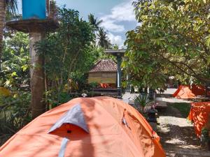 uma tenda laranja no meio de um jardim em Gecko Tropical inn em Gerung