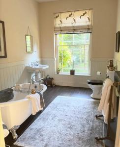 baño con bañera, lavabo y ventana en North Ormsby Manor, en Louth