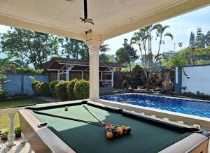 a pool table in front of a swimming pool at villa romi in Puncak
