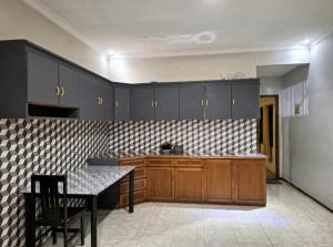 a kitchen with wooden cabinets and a table in it at villa romi in Puncak