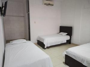 Habitación con 2 camas con sábanas blancas. en Bamboleo Club Zorritos en Zorritos