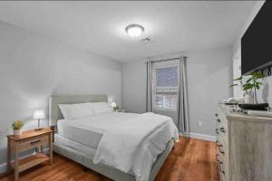 a white bedroom with a bed and a window at T&G Suites in Providence
