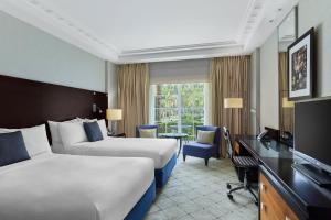 カイロにあるRenaissance Cairo Mirage City Hotelのベッド2台、デスク、テレビが備わるホテルルームです。