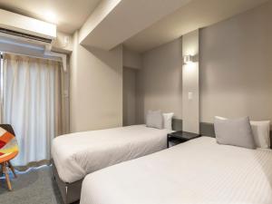 a hotel room with two beds and a window at Tabist Unihotel Midosuji Hommachi in Osaka