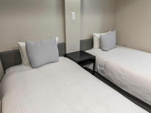 a room with two beds and a table between them at Tabist Unihotel Midosuji Hommachi in Osaka