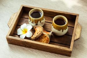 a wooden tray with two cups and a flower on it at Sabai Sathorn Service Apartment in Bangkok
