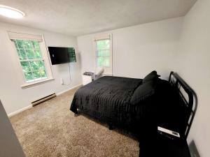 Dormitorio con cama negra y TV en 4-Bedroom House Close to Beach, en Salisbury