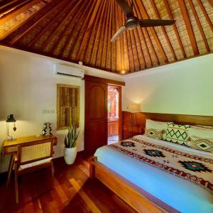 a bedroom with a bed and a ceiling fan at Villa Asrava Ubud in Ubud