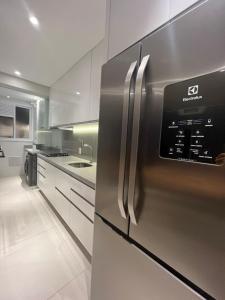 a large kitchen with a stainless steel refrigerator at Jurerê Beach Florianópolis ville romane in Florianópolis