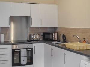 uma cozinha com armários brancos e um lavatório em Harbour Apartment em Nairn