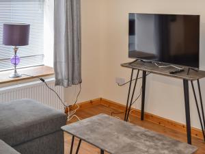 a living room with a flat screen tv and a couch at Harbour Apartment in Nairn