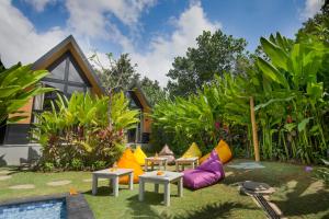 a garden with colorful furniture in front of a house at Le Cielo Resort Umalas by Maviba in Canggu