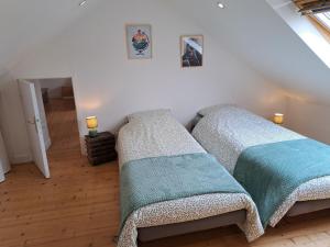 Duas camas num quarto com paredes brancas e pisos de madeira em Comfortable cottage close to the beach, Portsall, 2 canoes em Ploudalmézeau