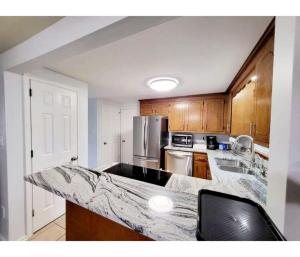 a kitchen with a marble counter top and wooden cabinets at 4-Bedroom House Close to Beach in Salisbury