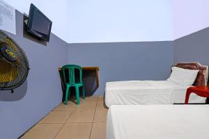 een kamer met 2 bedden en een groene stoel bij OYO 92893 Santana Residence Syariah in Bojongsalam