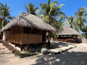 uma pequena cabana com telhado de palha e palmeiras em VILLA LANGIT TEDUH ROTE em Nembrala