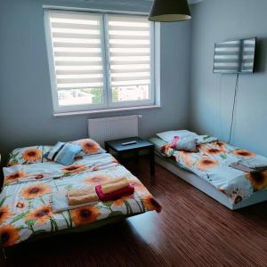 dwa łóżka w pokoju z dwoma oknami w obiekcie Zachodnia 8th floor apartment w Krakowie