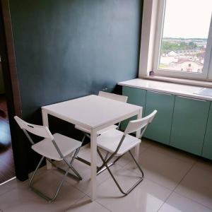 Biały stół i krzesła w pokoju z oknem w obiekcie Zachodnia 8th floor apartment w Krakowie