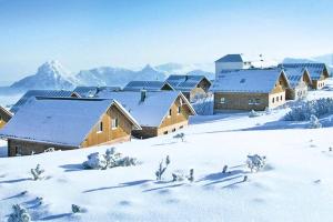 un grupo de edificios en la nieve con montañas en Feriendorf am Feuerkogel, Ebensee, en Ebensee
