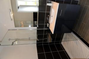a glass shower in a bathroom with black tiles at La Maison d'Hotes de Saint Leger in Saint-Léger-en-Yvelines