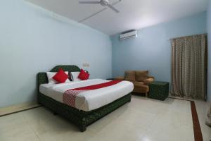 a bedroom with a bed and a chair in it at OYO Flagship Sandhra Apartments in Pūvār