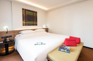 a bedroom with a large white bed with red pillows at Maitria Mode Sukhumvit 15 Bangkok - A Chatrium Collection in Bangkok