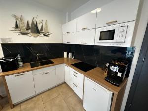 kuchnia z białymi szafkami i kuchenką mikrofalową w obiekcie Apartament Dorado w mieście Mielno