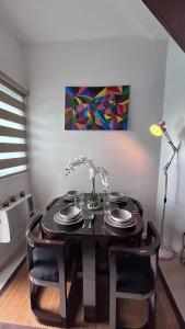 uma mesa de jantar com cadeiras pretas e um quadro em Kurlix Suites of Azure North em San Fernando