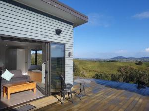 um pátio com um sofá e uma mesa num deque em Vineyard Vacation em Mangawhai