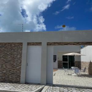 a building with two white garage doors and a patio at Rsolmar2023 in Tamandaré