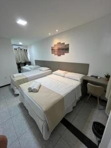 a bedroom with two beds and a desk at Pousada La Riviera - Pé na areia e Passeios em Maragogi in Maragogi