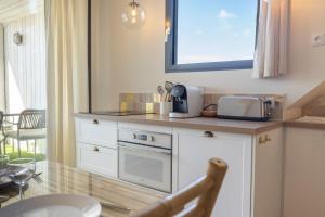 a kitchen with a counter with a tv on the wall at Les Voiles - Appart'hotel "La Galerne" in Carnac
