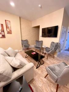 a living room with a couch and chairs and a tv at Uncork on Historic Main! in St. Charles
