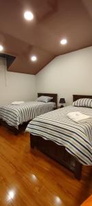 two beds in a room with wooden floors at Casa Ayacucho in Sucre