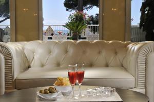 a white couch with two wine glasses on a table at Grand Hotel Playa in Lignano Sabbiadoro