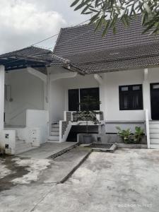 a white house with a porch and stairs at Sejahtera Homestay in Cangkringan