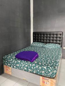 a bed with a black headboard and a green blanket at Sejahtera Homestay in Cangkringan
