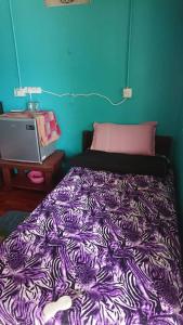 a bed in a room with a purple blanket at Barook Chalet in Mersing