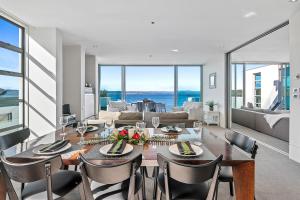 a dining room with a table and chairs and a living room at Taupo Penthouse in Taupo
