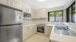 a kitchen with white cabinets and a stainless steel refrigerator at Anne Street Monte - Vista in Port Macquarie