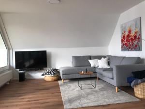 sala de estar con sofá gris y TV de pantalla plana en Ferienwohnung Plön am See, en Plön