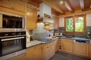 a kitchen with wooden cabinets and stainless steel appliances at Chalet Batieu - OVO Network in La Clusaz