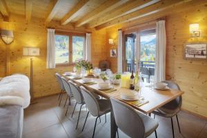 a dining room with a long wooden table and chairs at Chalet Batieu - OVO Network in La Clusaz