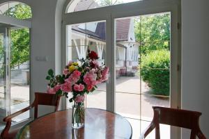 een vaas met bloemen op een tafel voor een raam bij Partvilla Balatonboglar in Balatonboglár