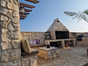 an outdoor patio with a stone fireplace and a couch at Oikos Selinolithos in Alaminos